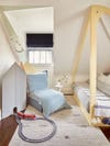 Kid's room with soft yellow canopy bed and train track going into wall. 